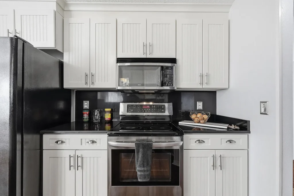 Bright kitchen with white cabinets, dark countertops and stainless steel appliances