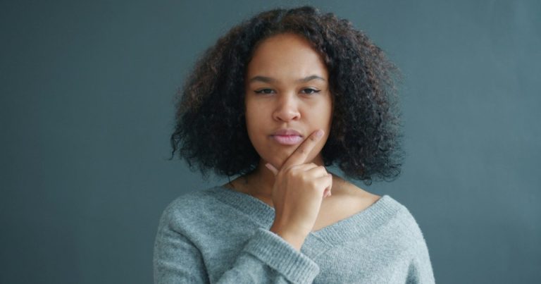 Woman thinking with her hand on her chin, like a buyer unsure about signing a buyer broker agreement