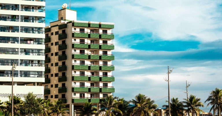 Older beachfront condo building with balconies and palm trees, the kind of building where special assessments often fund repairs