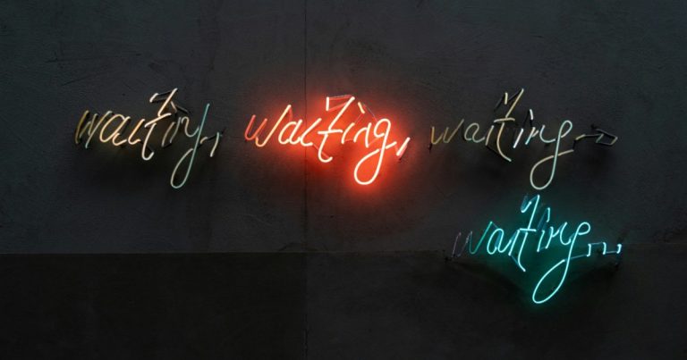 Neon sign reading waiting, waiting, waiting, like a buyer waiting on their home to sell with a home sale contingency
