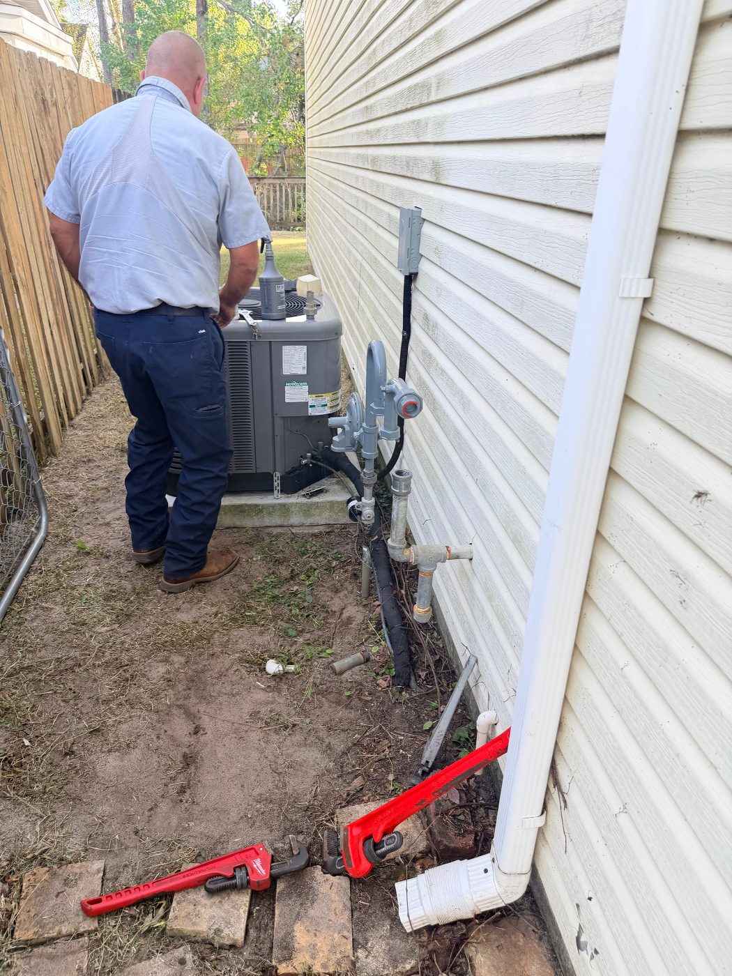 Okaloosa Gas technician working on the gas meter and piping beside the house