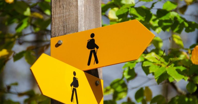 Two yellow trail signs pointing in different directions, like under contract and pending