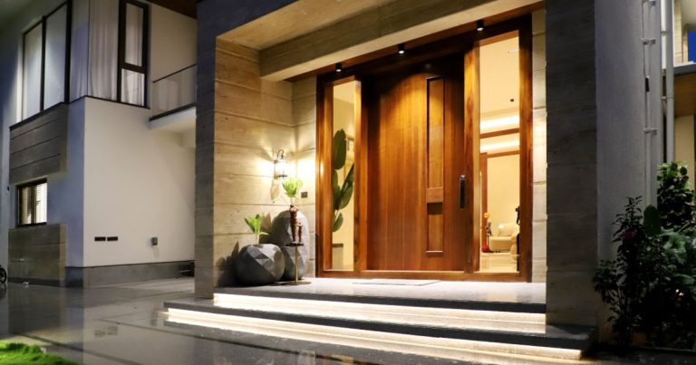 Modern home with a lit front entry at dusk